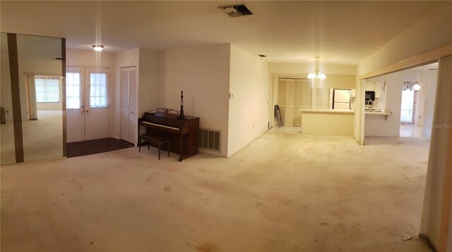 living room featuring light colored carpet, french doors, and a chandelier