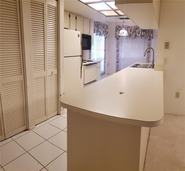 kitchen featuring white appliances, white cabinets, sink, hanging light fixtures, and light tile patterned flooring