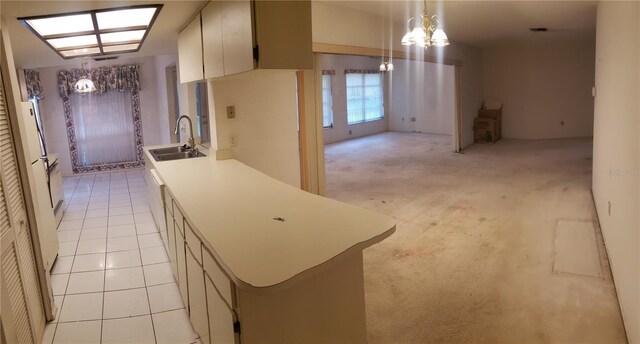 kitchen featuring a chandelier, sink, light carpet, and hanging light fixtures