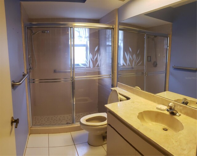 bathroom featuring tile patterned floors, toilet, vanity, and an enclosed shower