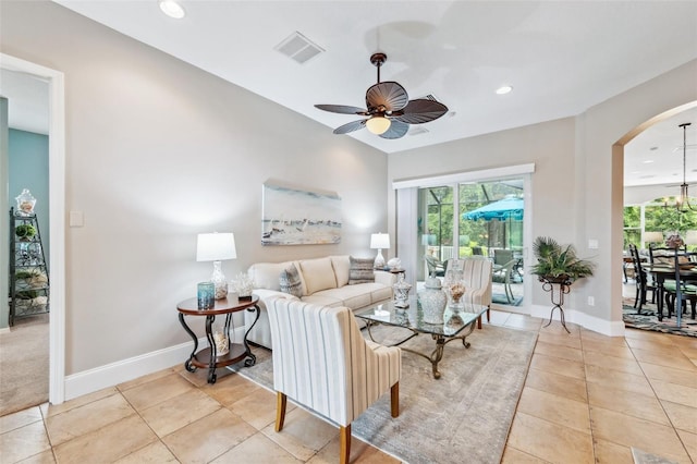 tiled living room with ceiling fan with notable chandelier