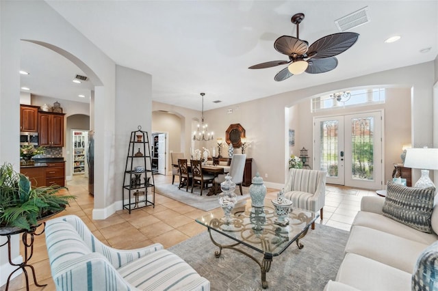 tiled living room featuring french doors and ceiling fan with notable chandelier