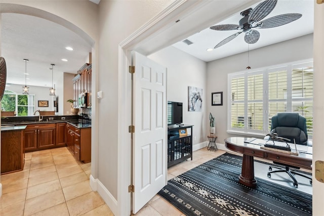 tiled home office featuring ceiling fan and sink