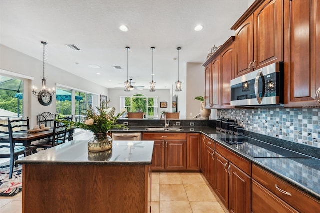 kitchen with appliances with stainless steel finishes, decorative light fixtures, sink, a center island, and kitchen peninsula