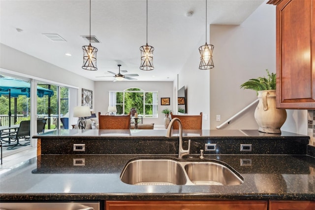 kitchen with pendant lighting, dishwasher, sink, dark stone counters, and ceiling fan