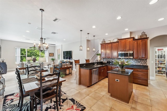 kitchen with pendant lighting, tasteful backsplash, sink, kitchen peninsula, and stainless steel appliances