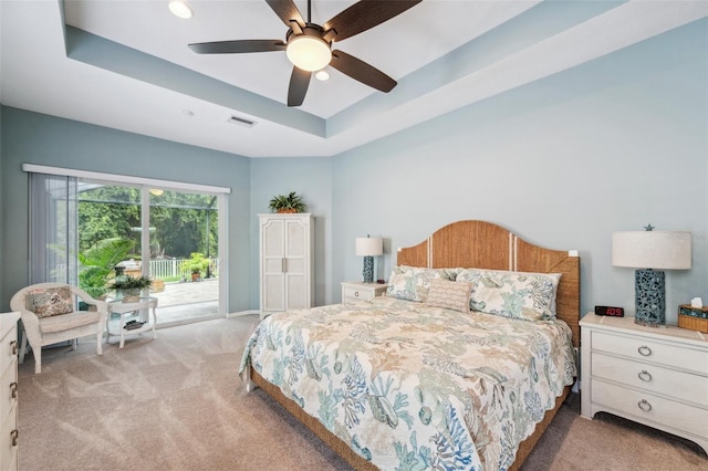 bedroom featuring light carpet, access to exterior, a raised ceiling, and ceiling fan