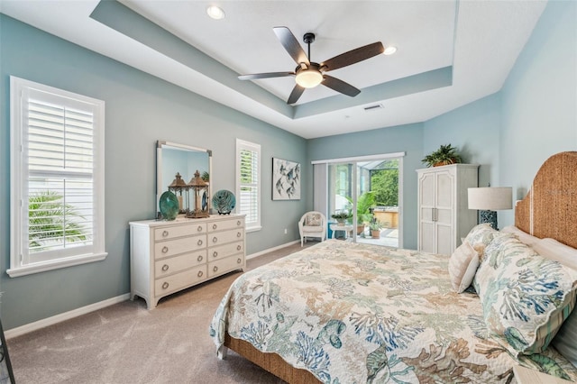 bedroom featuring ceiling fan, light colored carpet, and a raised ceiling