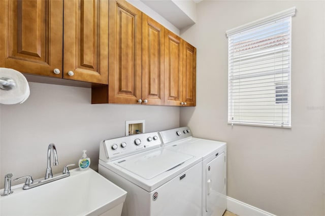 clothes washing area featuring cabinets, washing machine and clothes dryer, sink, and a wealth of natural light