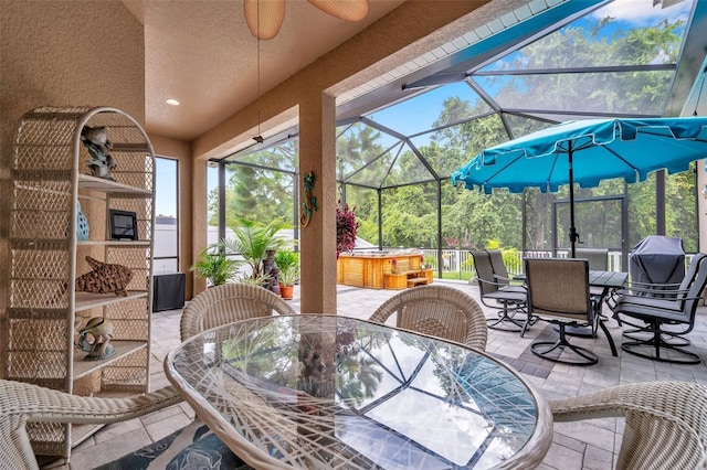 view of patio with a hot tub, ceiling fan, and glass enclosure