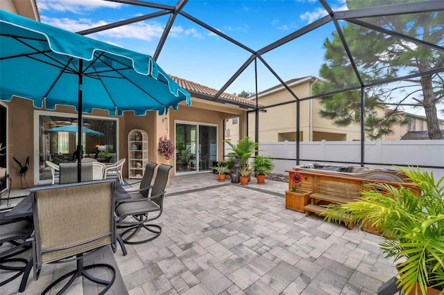 view of patio / terrace with a hot tub and glass enclosure