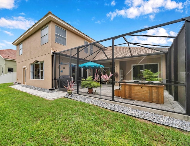 back of house featuring a hot tub, a yard, glass enclosure, and a patio area