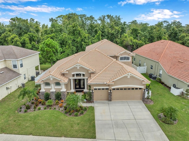 view of front of property featuring a garage, cooling unit, and a front yard