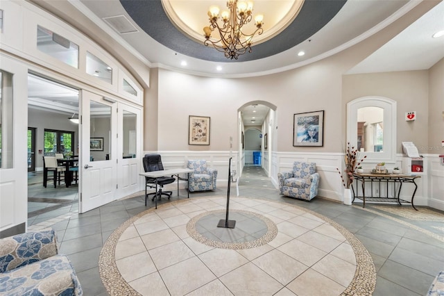 interior space with crown molding, a tray ceiling, tile patterned floors, and an inviting chandelier