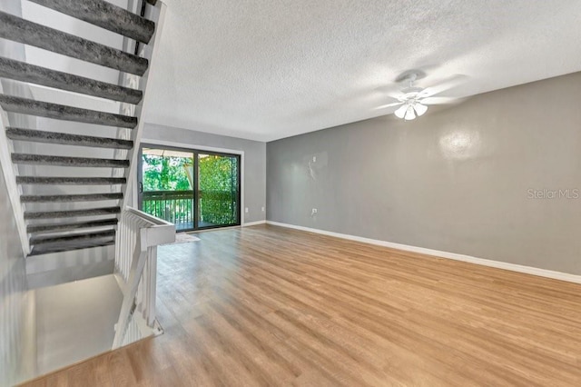 unfurnished living room with ceiling fan, wood-type flooring, and a textured ceiling