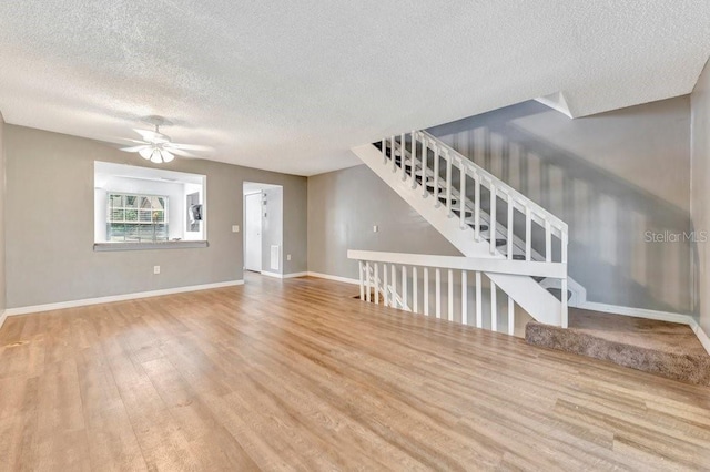 unfurnished living room with ceiling fan, a textured ceiling, and light hardwood / wood-style floors