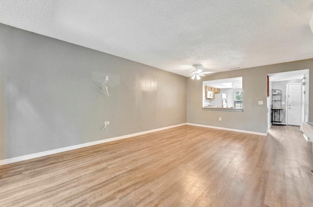 empty room with ceiling fan, a textured ceiling, and light hardwood / wood-style flooring