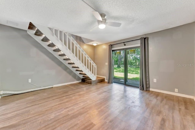 interior space featuring ceiling fan, wood-type flooring, and a textured ceiling