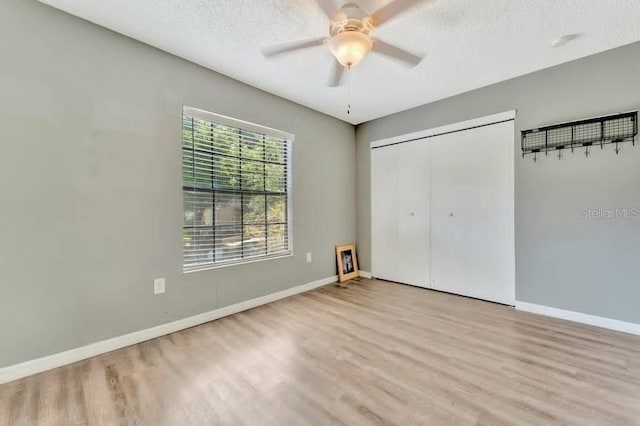 unfurnished bedroom with ceiling fan, a textured ceiling, a closet, and light hardwood / wood-style flooring