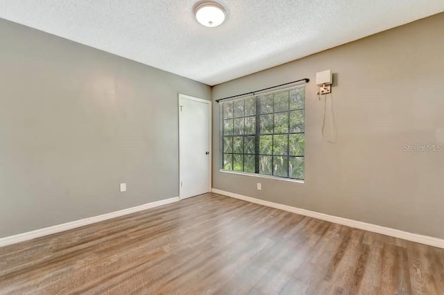 unfurnished room featuring hardwood / wood-style floors and a textured ceiling