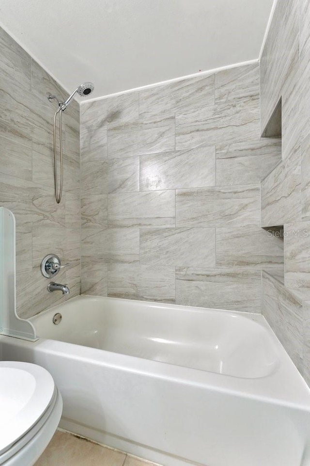 bathroom featuring tile patterned floors, toilet, and tiled shower / bath