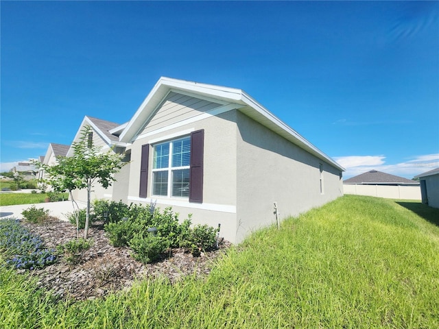 view of property exterior with a lawn, fence, and stucco siding