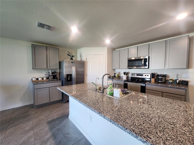 kitchen featuring stainless steel appliances, sink, a textured ceiling, dark tile patterned flooring, and gray cabinetry