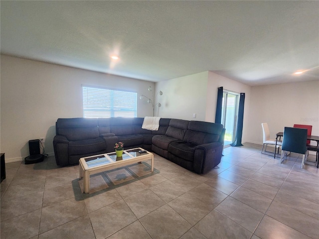 living area featuring a textured ceiling, light tile patterned flooring, and baseboards