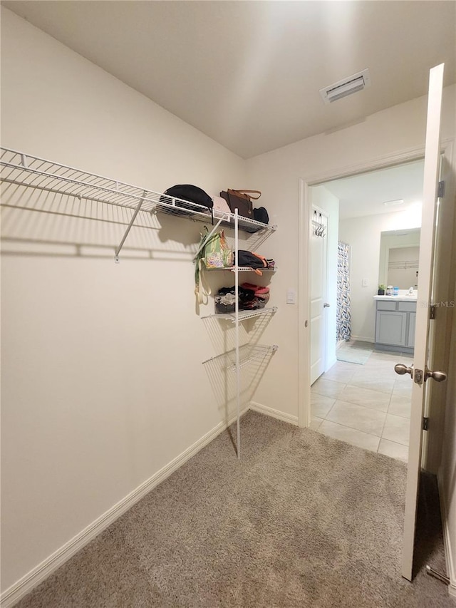 spacious closet featuring light carpet, light tile patterned flooring, and visible vents