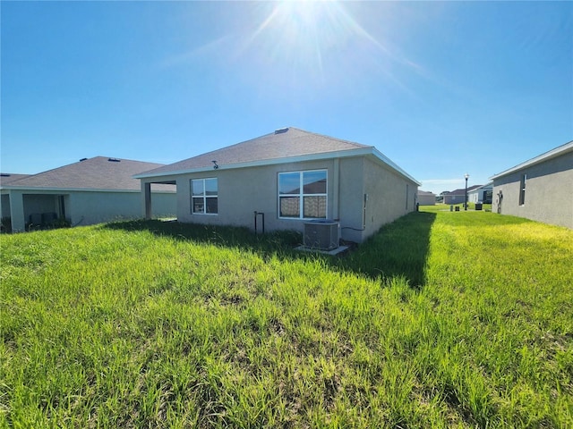 back of property featuring central AC unit and a lawn