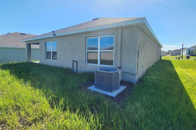 view of home's exterior with a lawn, central AC, and stucco siding