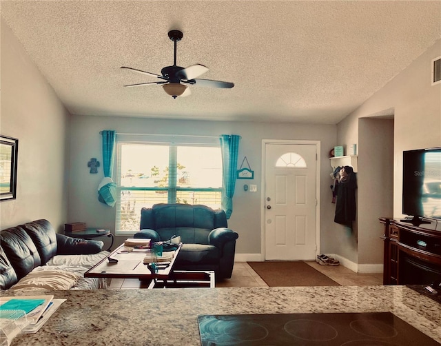 living area featuring a textured ceiling, visible vents, light tile patterned flooring, and a ceiling fan