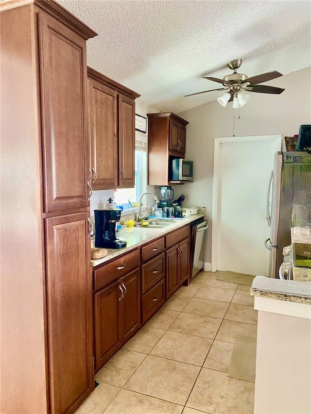 kitchen with light tile patterned floors, light countertops, appliances with stainless steel finishes, a ceiling fan, and a sink