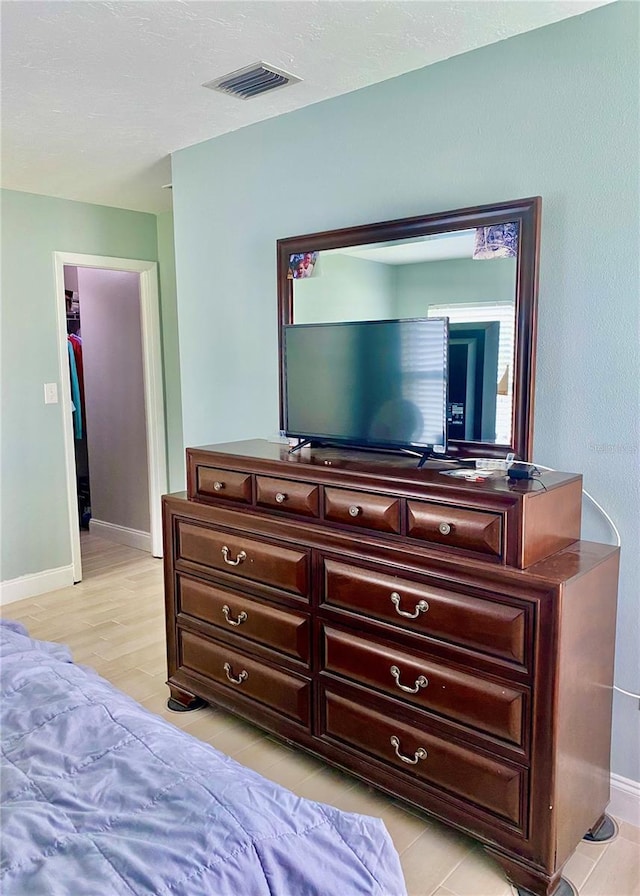 bedroom featuring light wood-style floors, visible vents, and baseboards