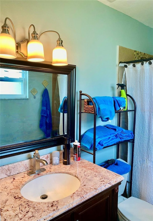 bathroom featuring toilet, curtained shower, and vanity