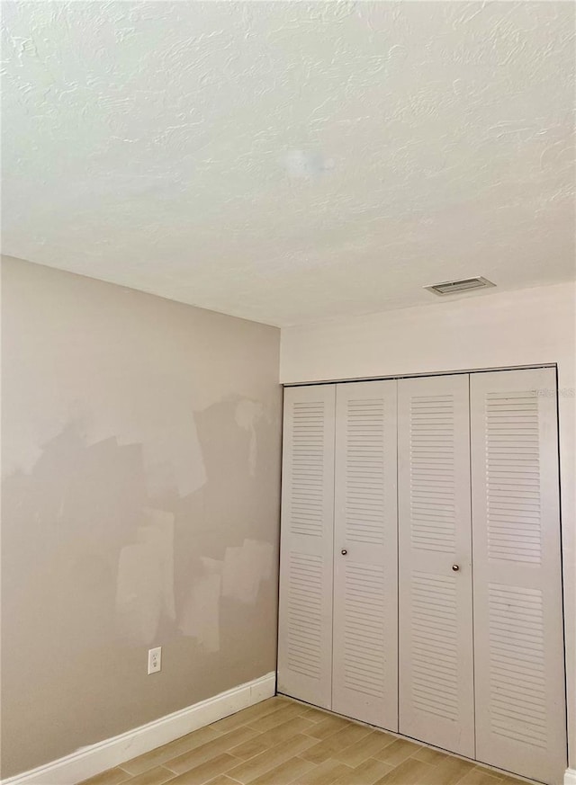 unfurnished bedroom with light wood-style flooring, a closet, visible vents, and baseboards