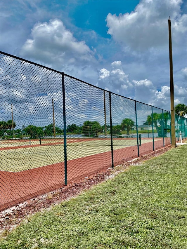 view of tennis court featuring a yard and fence