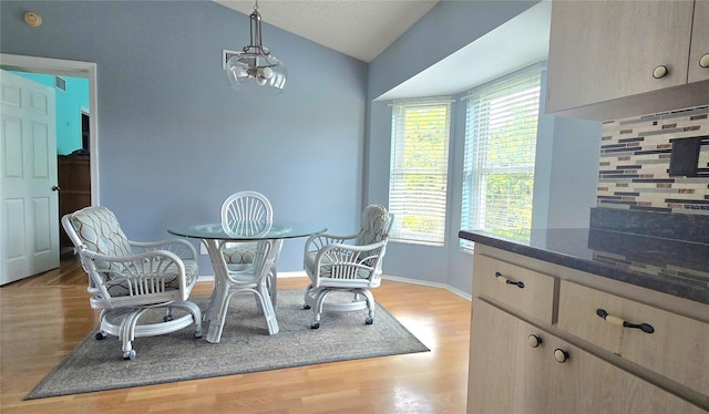 dining space with light hardwood / wood-style floors and lofted ceiling