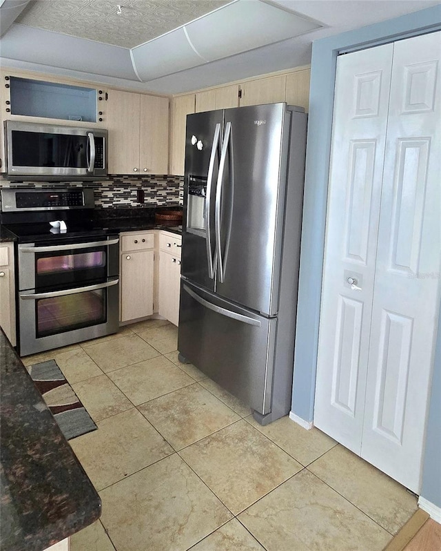 kitchen with light brown cabinetry, stainless steel appliances, decorative backsplash, a textured ceiling, and light tile patterned floors