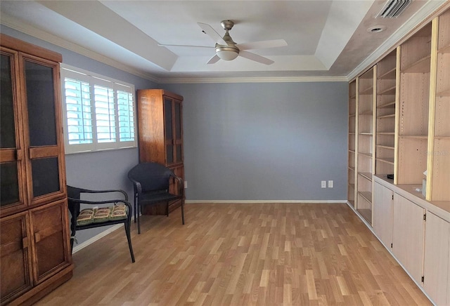 sitting room featuring light hardwood / wood-style floors, ceiling fan, a raised ceiling, and crown molding