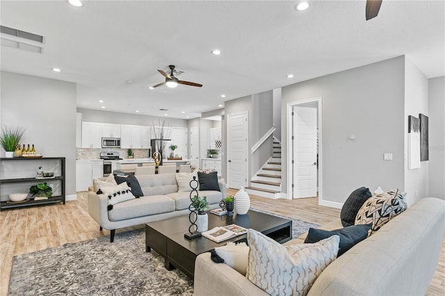 living room with ceiling fan, light wood-style flooring, recessed lighting, visible vents, and stairs