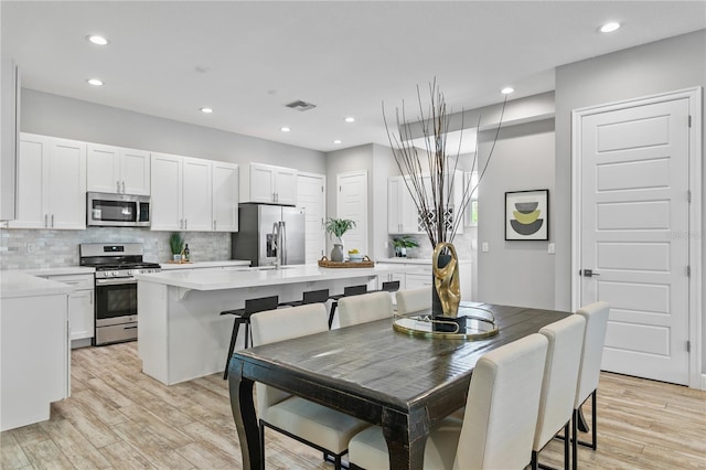 kitchen featuring light countertops, visible vents, decorative backsplash, appliances with stainless steel finishes, and light wood-style floors