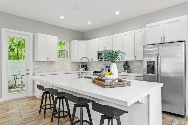 kitchen featuring stainless steel appliances, backsplash, a sink, and light countertops