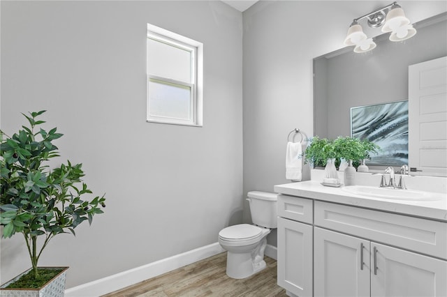 bathroom with vanity, wood finished floors, toilet, and baseboards