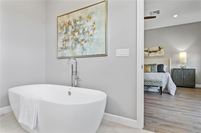 bathroom featuring a freestanding bath, visible vents, and baseboards