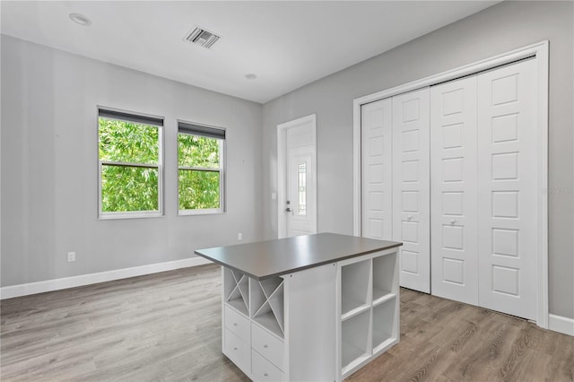 unfurnished office featuring light wood-style flooring, visible vents, and baseboards