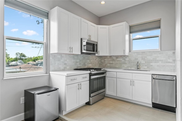 kitchen with stainless steel appliances, light countertops, a sink, and decorative backsplash