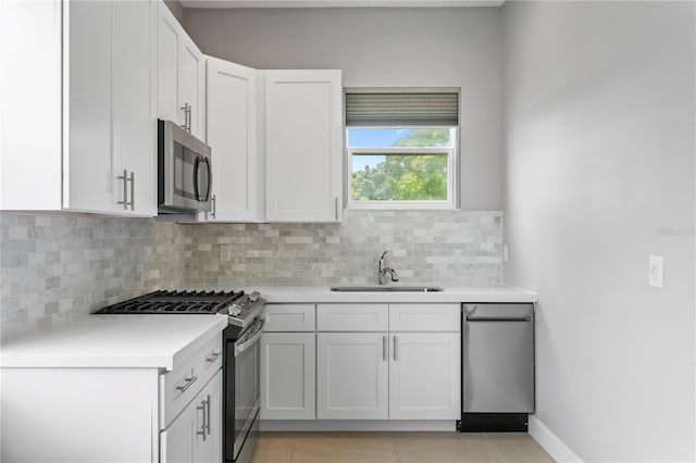 kitchen featuring tasteful backsplash, appliances with stainless steel finishes, light countertops, white cabinetry, and a sink