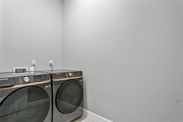 washroom featuring laundry area, washing machine and clothes dryer, and baseboards