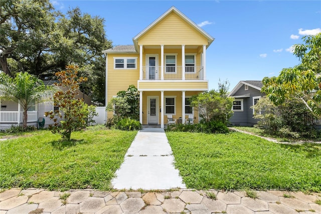 view of front of property featuring a balcony, covered porch, and a front lawn